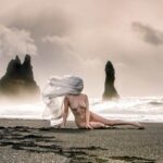 Stonetree Creative - Nude woman laying on black sand beach in Iceland