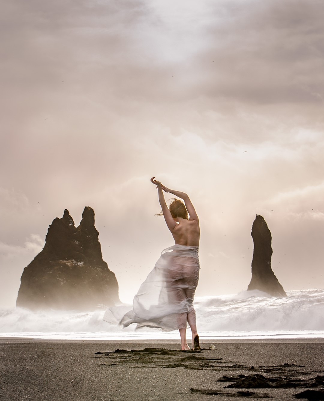woman in sheer fabric on beach in Iceland
