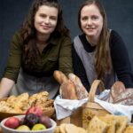 two women bakers in front of their baked goods