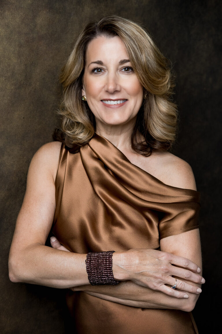 a woman with shoulder length hair wearing a copper colored dress and smiling in a personal branding portrait