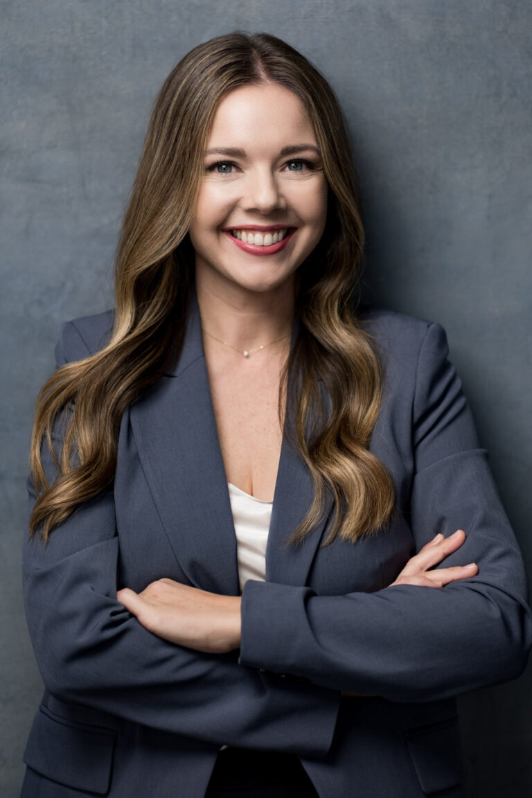 a woman with long hair wearing a suit and smiling in a personal branding portrait